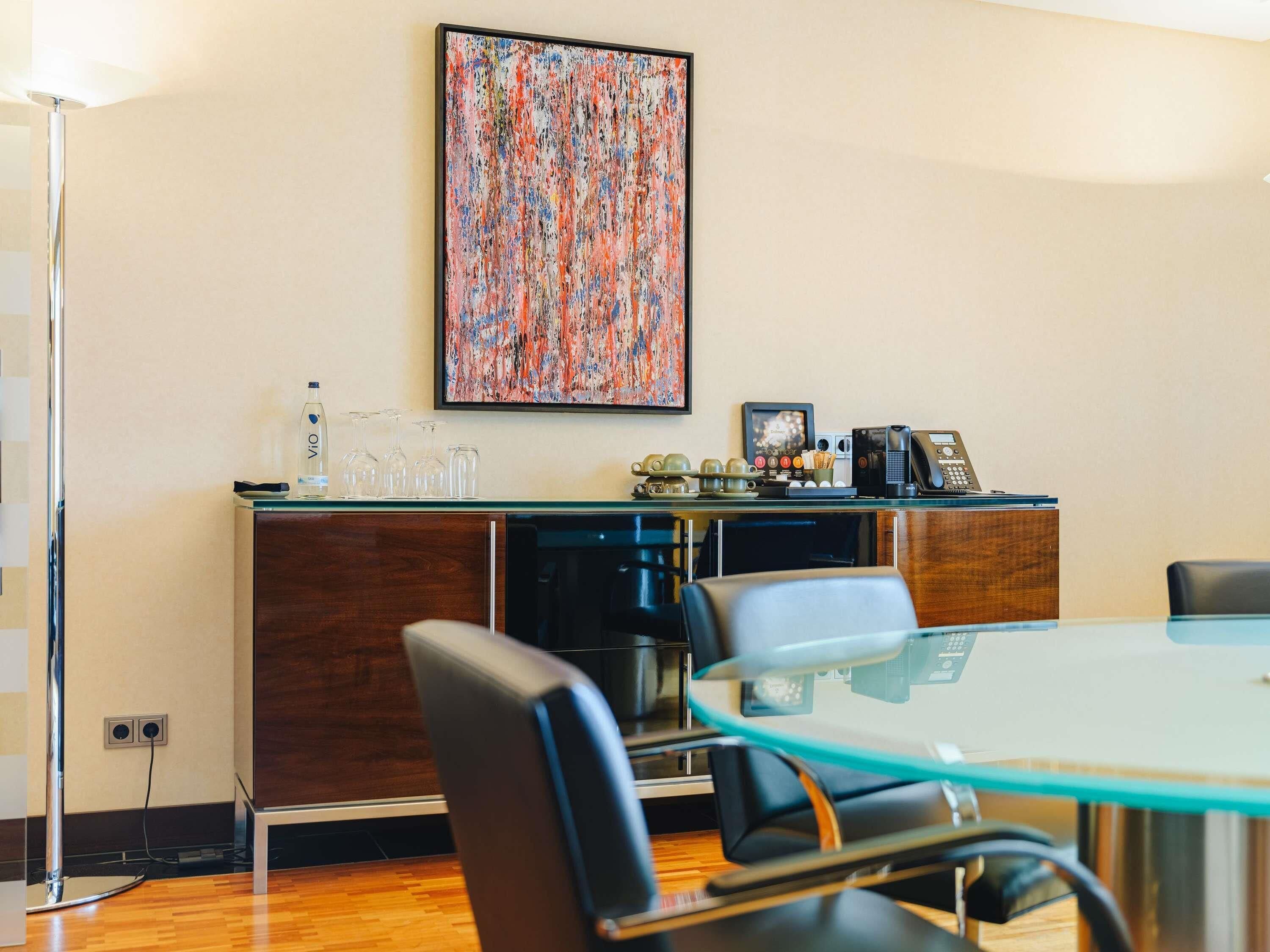 A modern kitchen with a glass table, wooden cabinets, and a coffee machine.