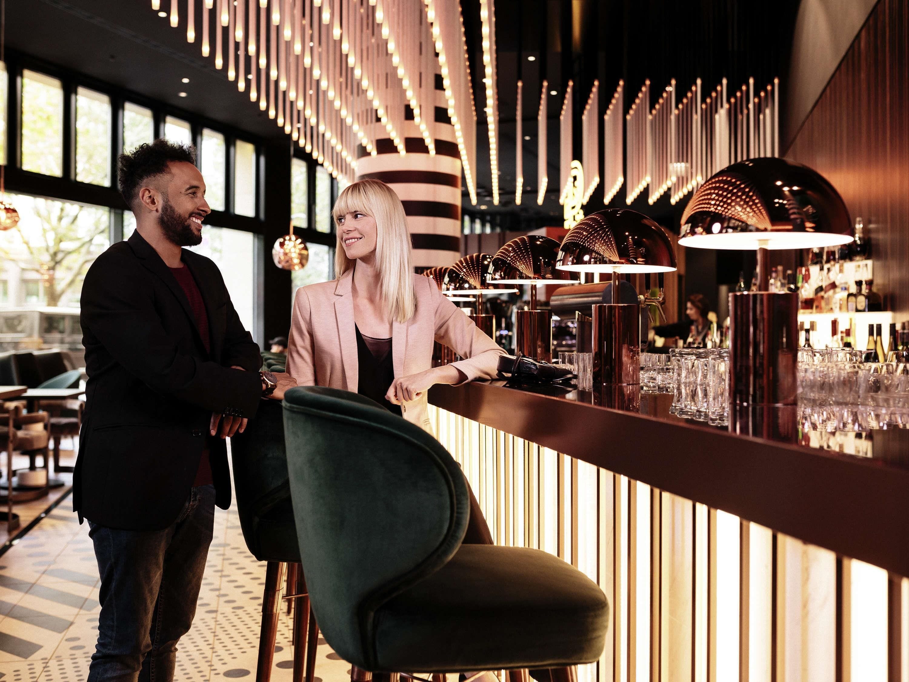Un área de bar moderna con mostrador, taburetes y un diseño de pared con motivos.