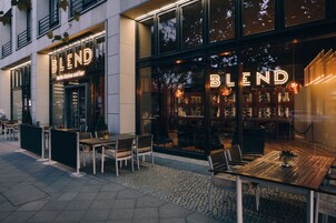 An exterior of a restaurant named 'Blend' with outdoor seating and a modern glass facade.