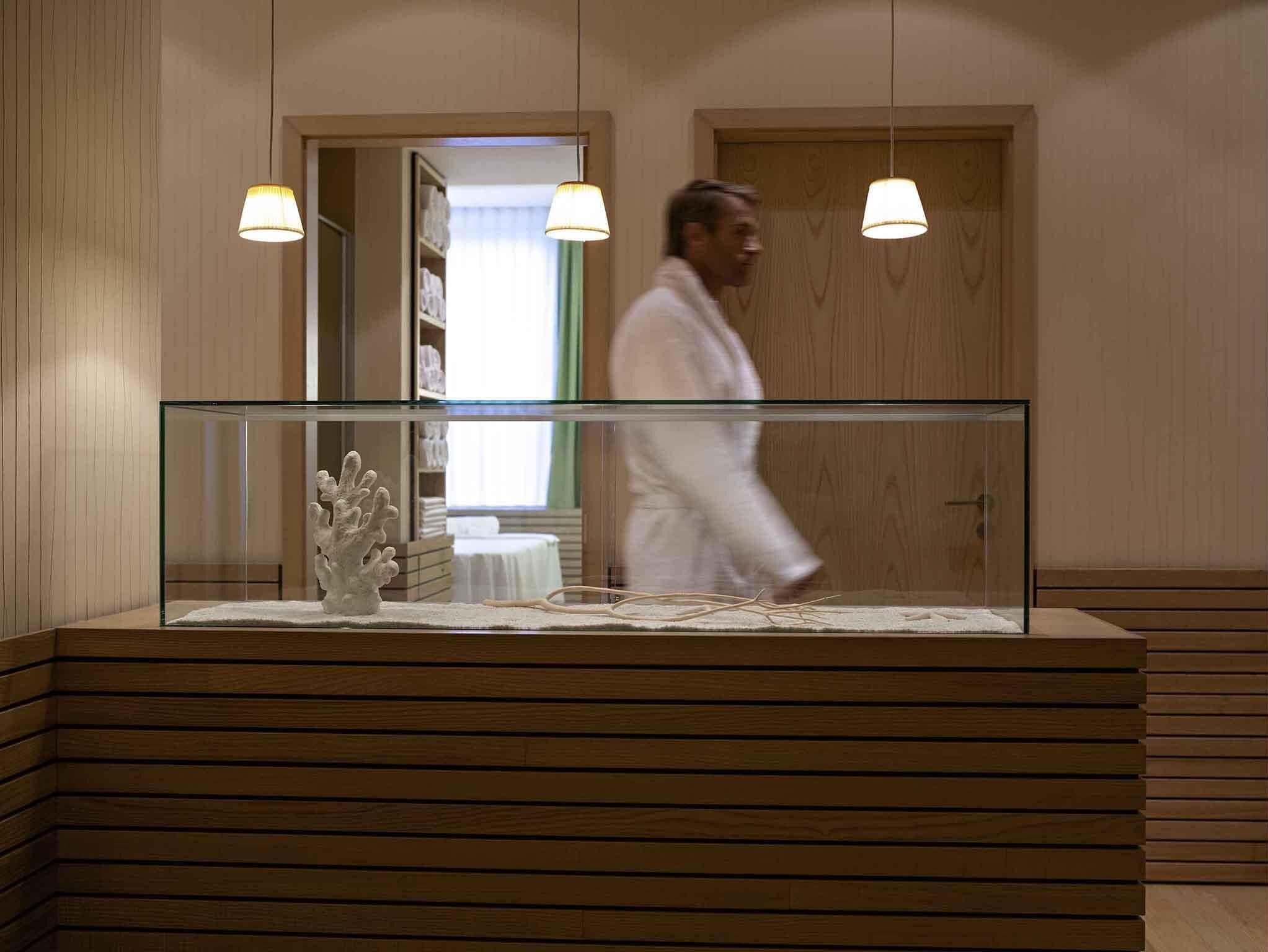 A modern bathroom with a glass partition, wooden paneling, and pendant lighting.