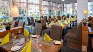Un ristorante con diversi tavoli apparecchiati, caratterizzato da interni moderni e ampie vetrate.