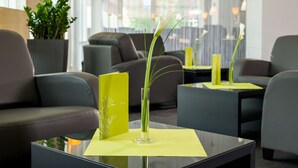 Una hall moderna con divani in pelle, un tavolino da caffè in vetro e un vaso con una pianta.