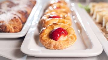 A tray of pastries including a strawberry-filled pastry and a glazed one.