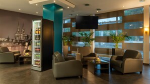 Una hall moderna con divani in pelle, un minibar, ampie finestre e una televisione a schermo piatto.