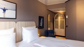 Une chambre d’hôtel avec un lit, une chaise, un miroir et un tableau encadré au mur.