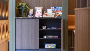 Une étagère avec des jeux de société, une plante en pot et un jouet en peluche.