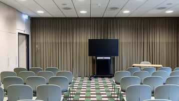 A conference room with rows of chairs, a large flat-screen TV, and a checkered carpet.