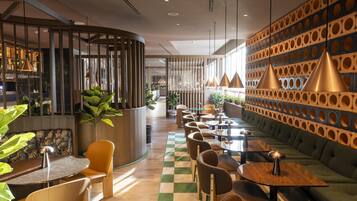 Un restaurant moderne avec un sol à carreaux, des meubles en bois et un mur décoré de motifs.