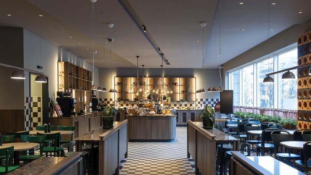Un restaurant moderne avec un sol à carreaux, des meubles en bois et des luminaires suspendus.