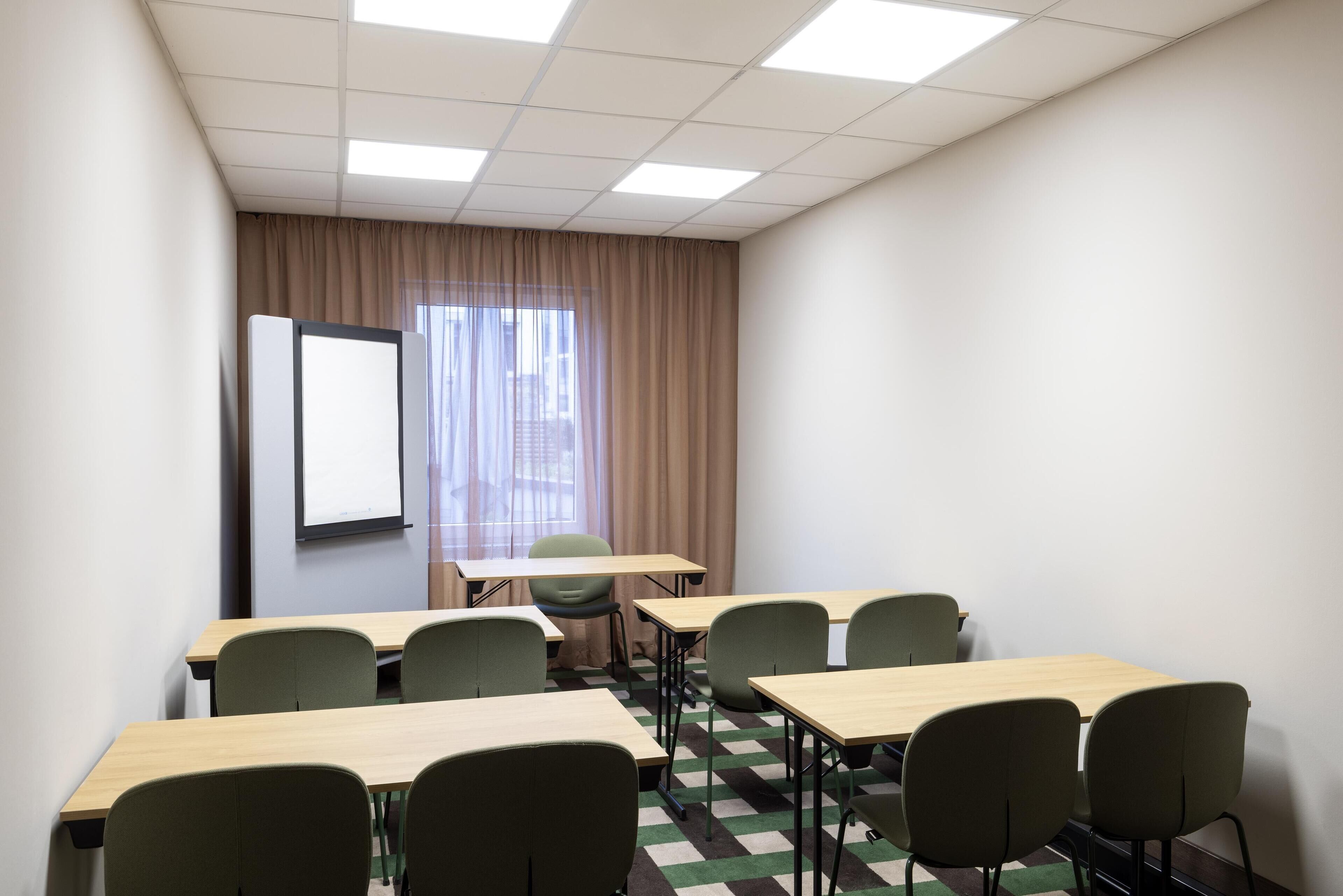 Une salle de conférence équipée d’un écran de projection, d’une grande fenêtre avec des rideaux, ainsi que de plusieurs tables et chaises.