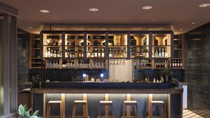 Un espace bar avec des étagères remplies de bouteilles, de verres et de tabourets.