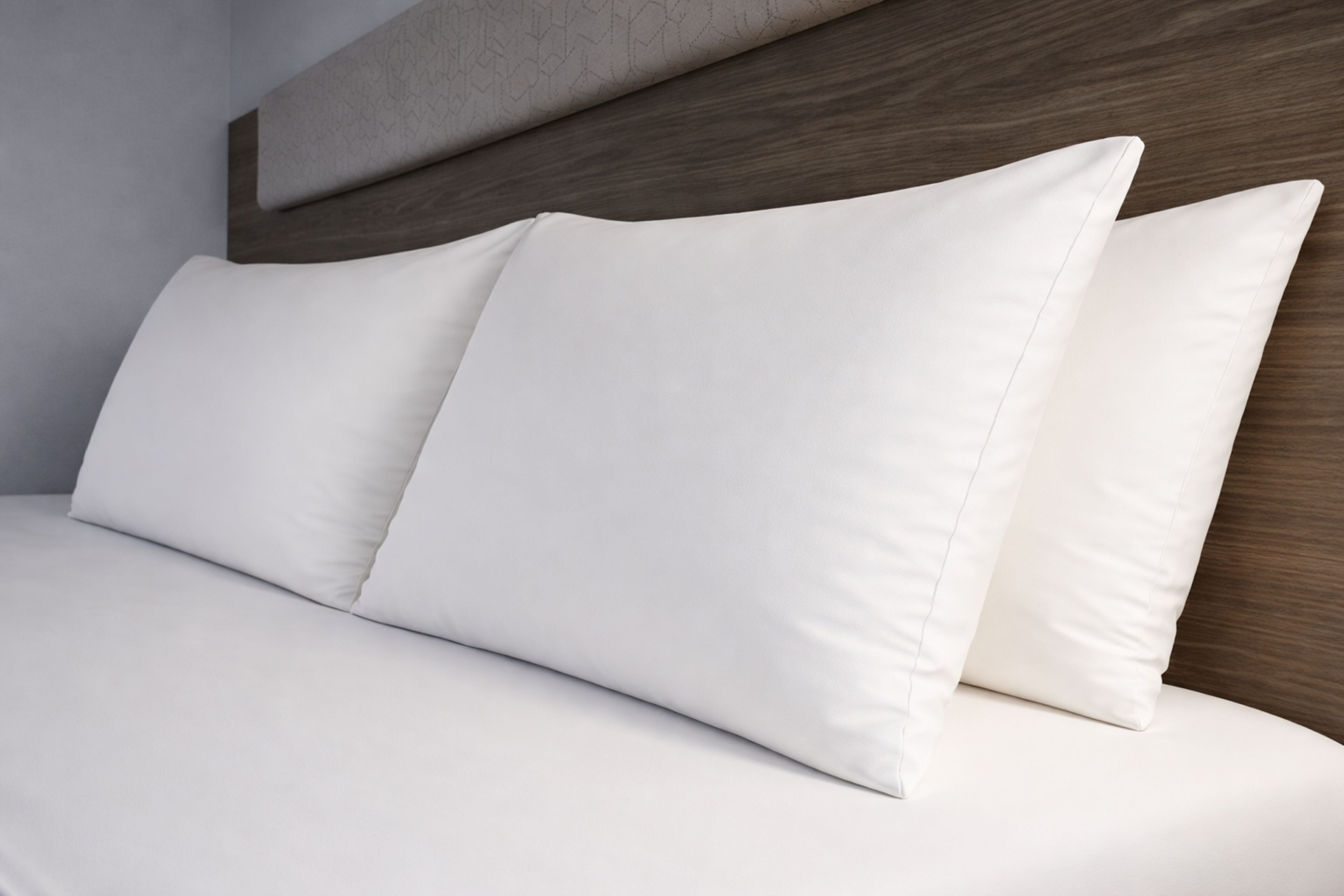 A bed with white bedding and a wooden headboard.