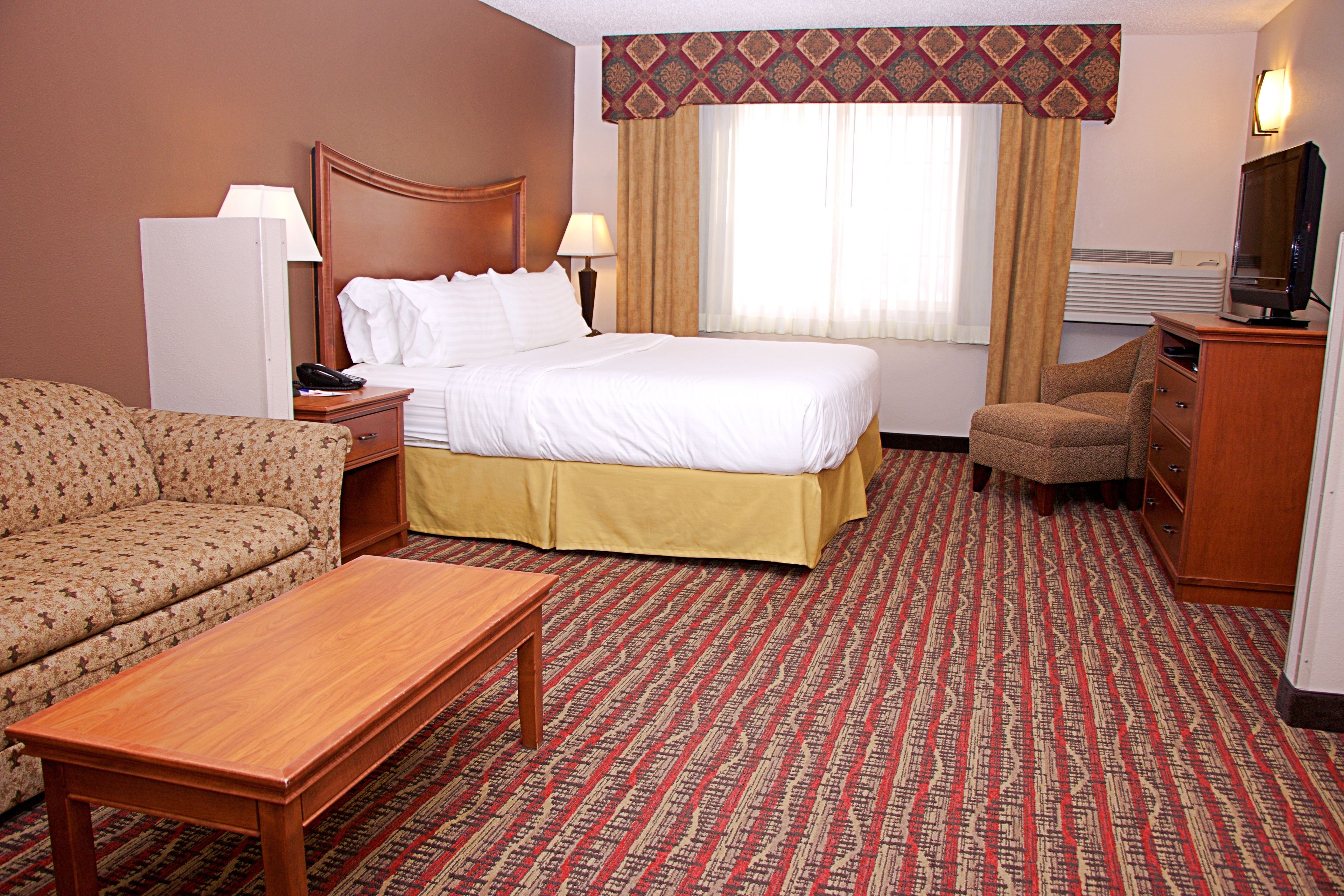 Habitación de hotel con cama, sofá, escritorio, silla y televisor.
