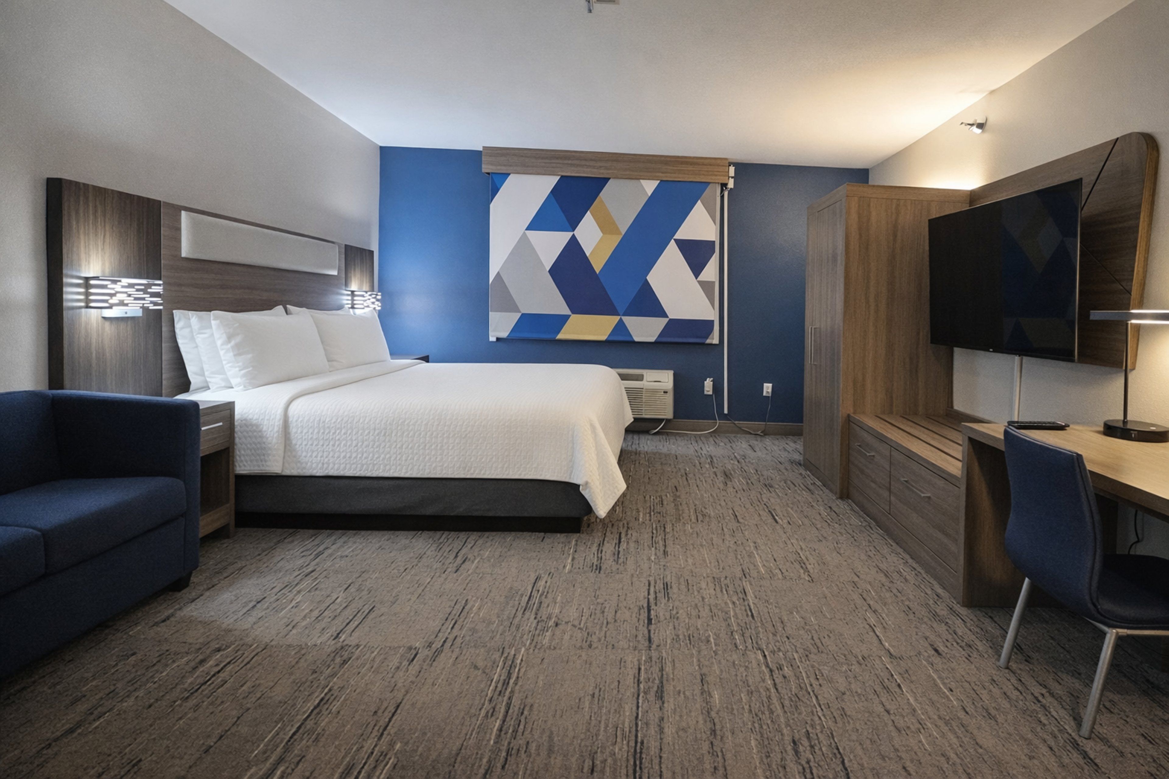 A hotel room with a bed, a desk, a TV, and a couch.