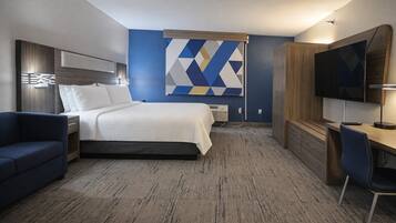 A hotel room with a bed, a desk, a TV, and a couch.