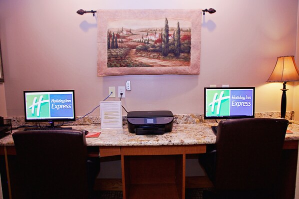 A hotel room with two monitors displaying the Holiday Inn Express logo, a printer, and a painting on the wall. - Holiday Inn Express & Suites Fort Pierre by IHG (Fort Pierre)