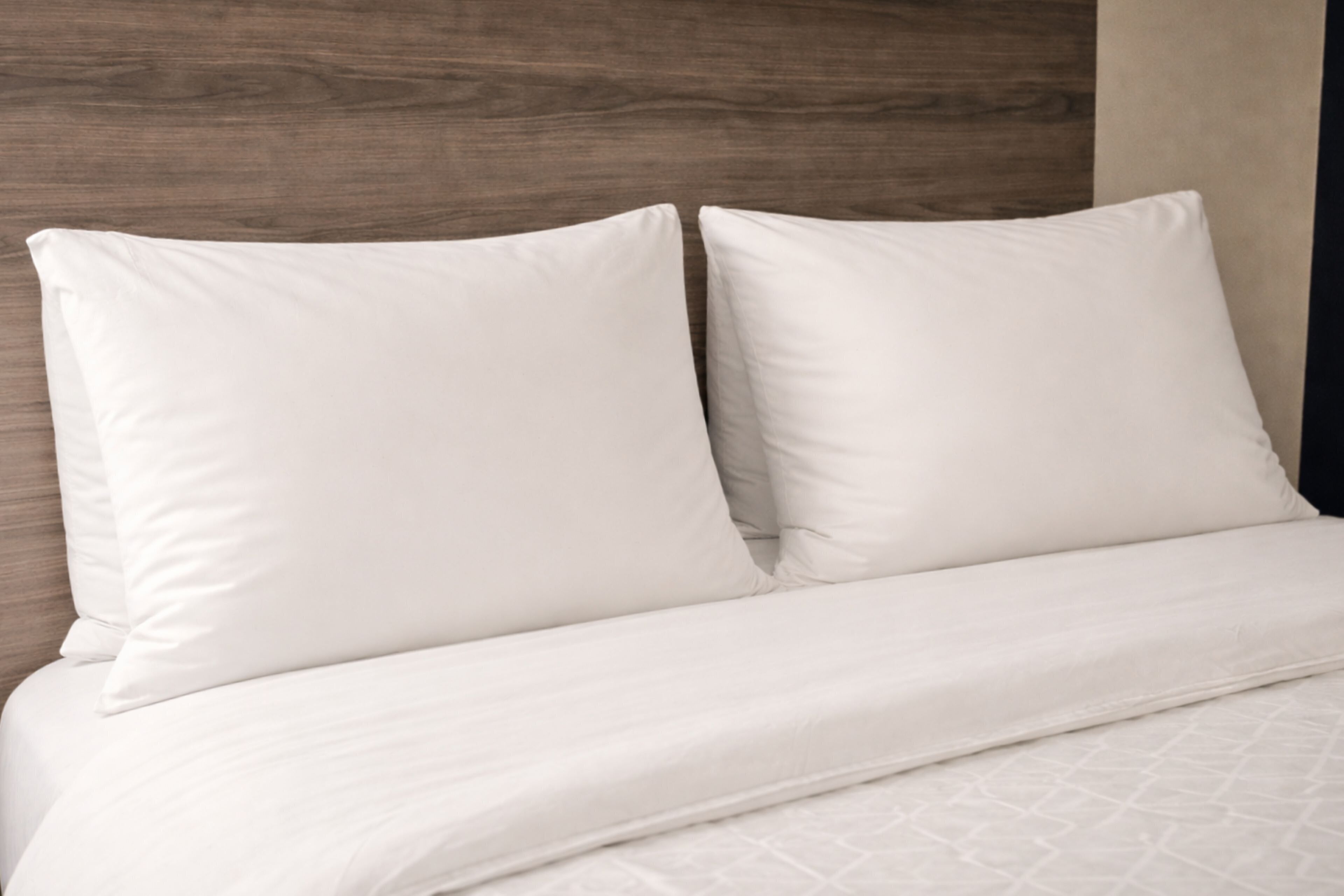 Una cama con ropa blanca y un cabecero de madera.