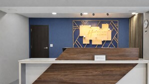 A reception desk with a wooden finish, a blue wall, and a clock on the right.