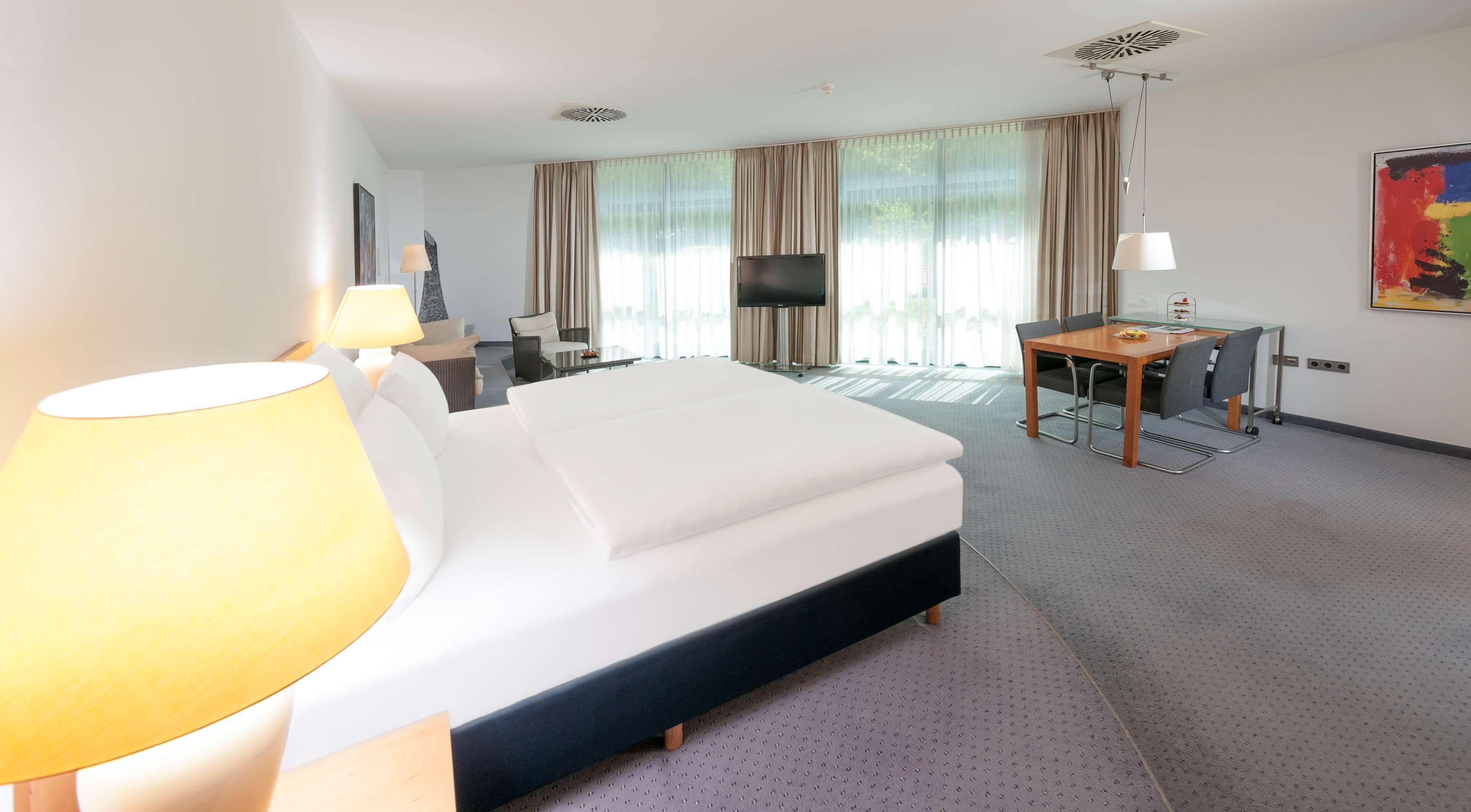 Une chambre d’hôtel avec un grand lit, un bureau, une chaise, une télévision et une lampe.