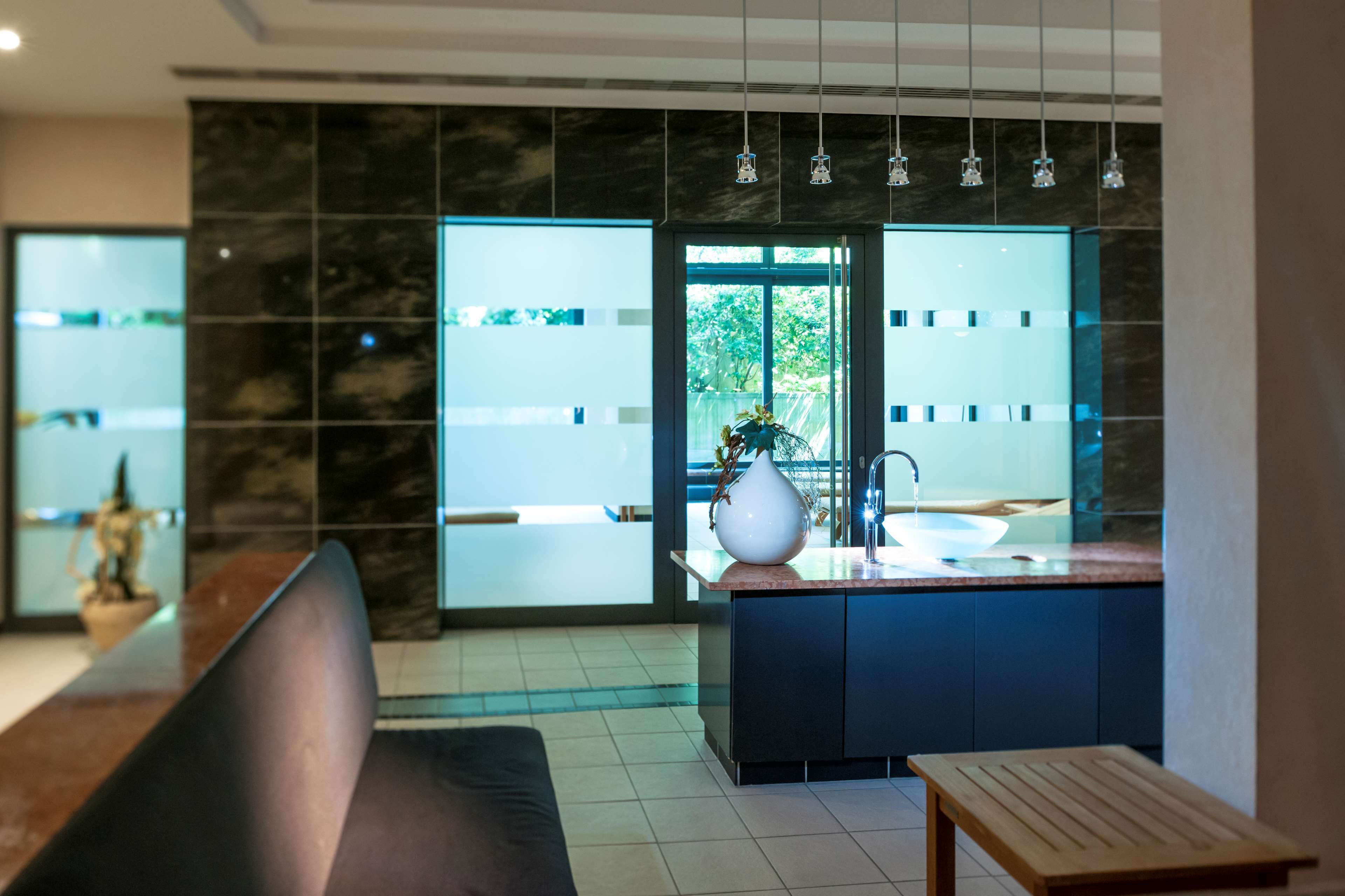 A modern kitchen with a marble backsplash, a sink, and a vase with flowers.