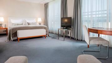 A hotel room with a bed, a desk, a television, and a chair.