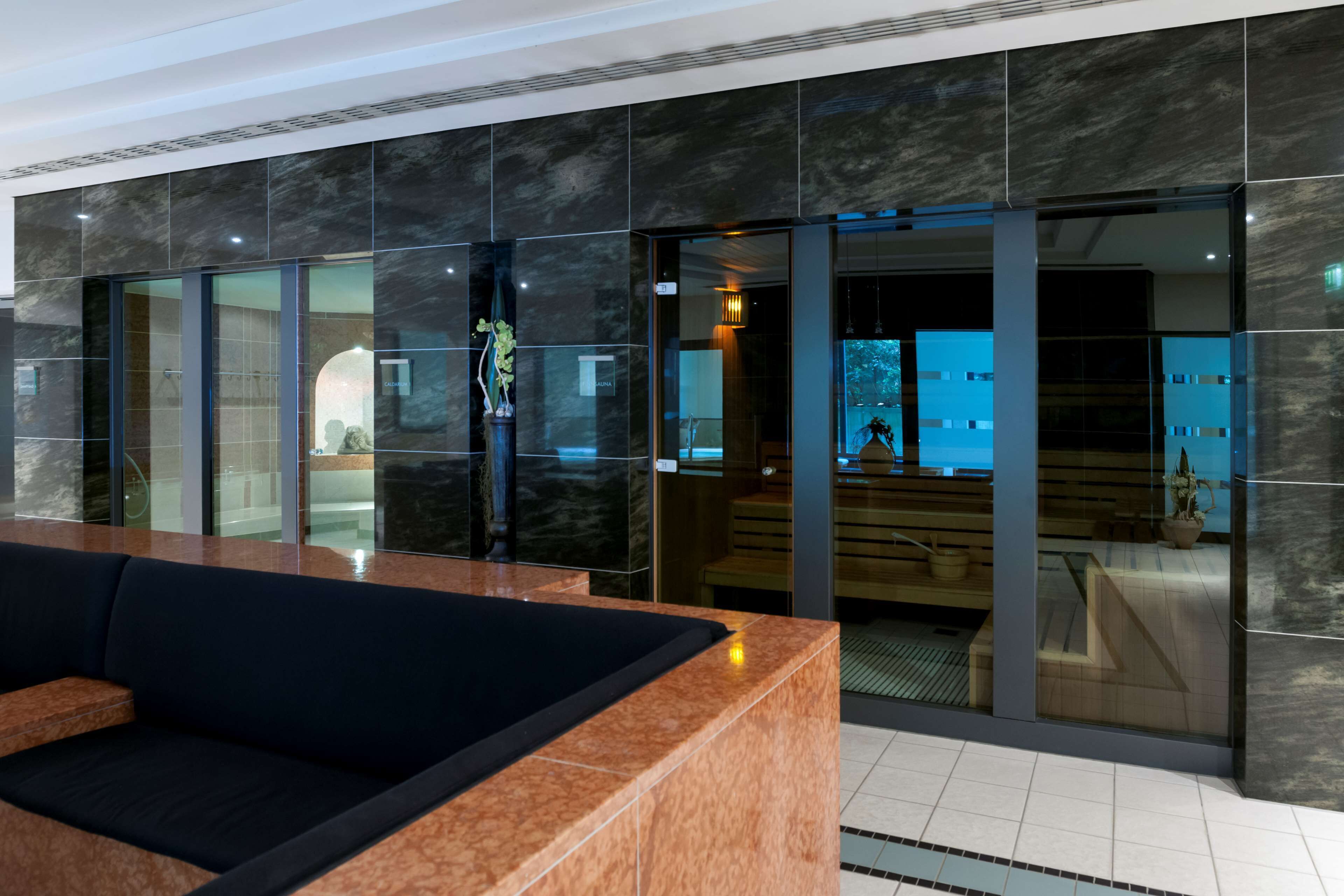 A modern lobby with a reception desk, seating area, and a glass door leading to a spa area.