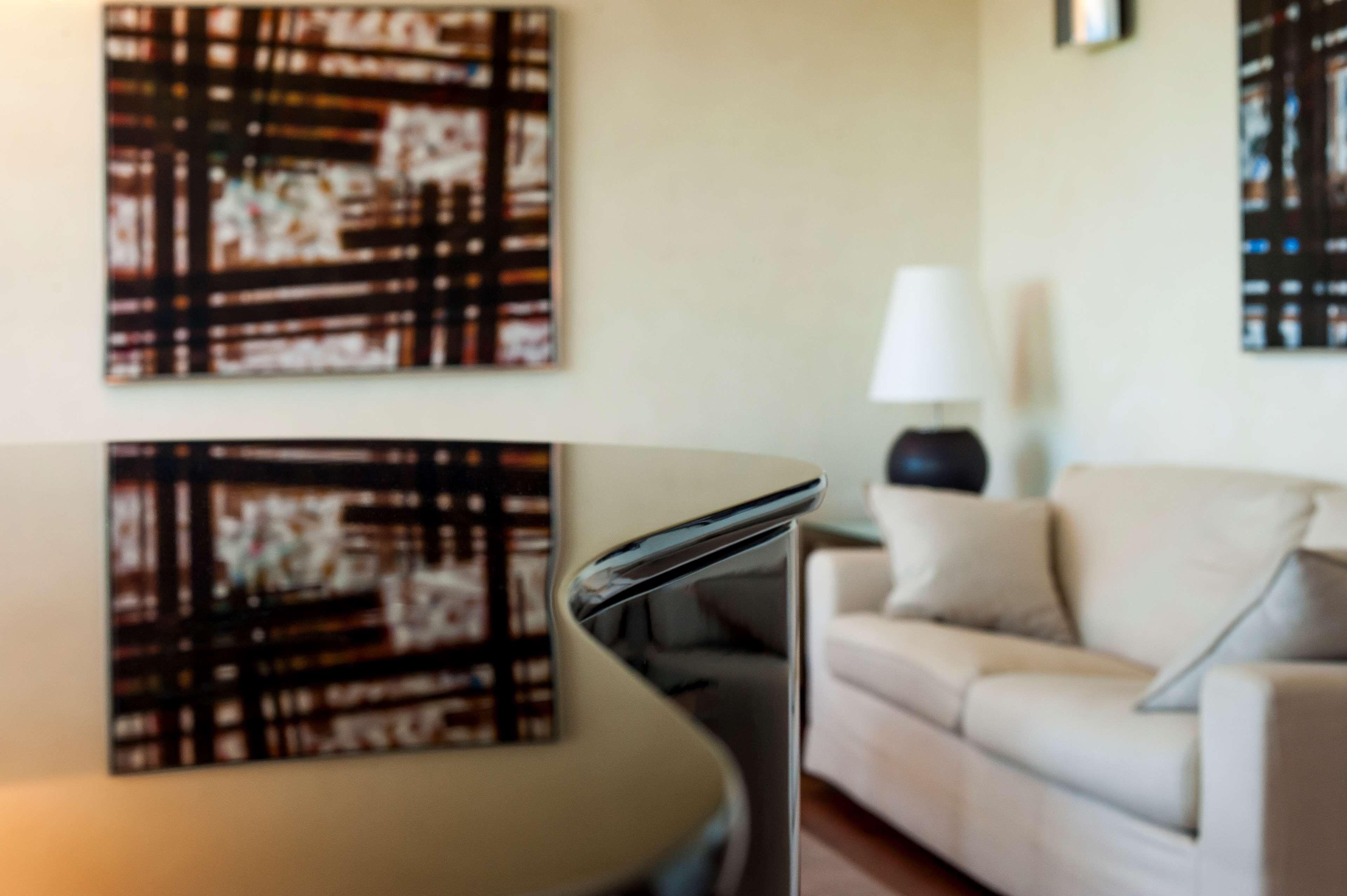 A modern living room with a curved sofa, a side table with a lamp, and abstract artwork on the walls.