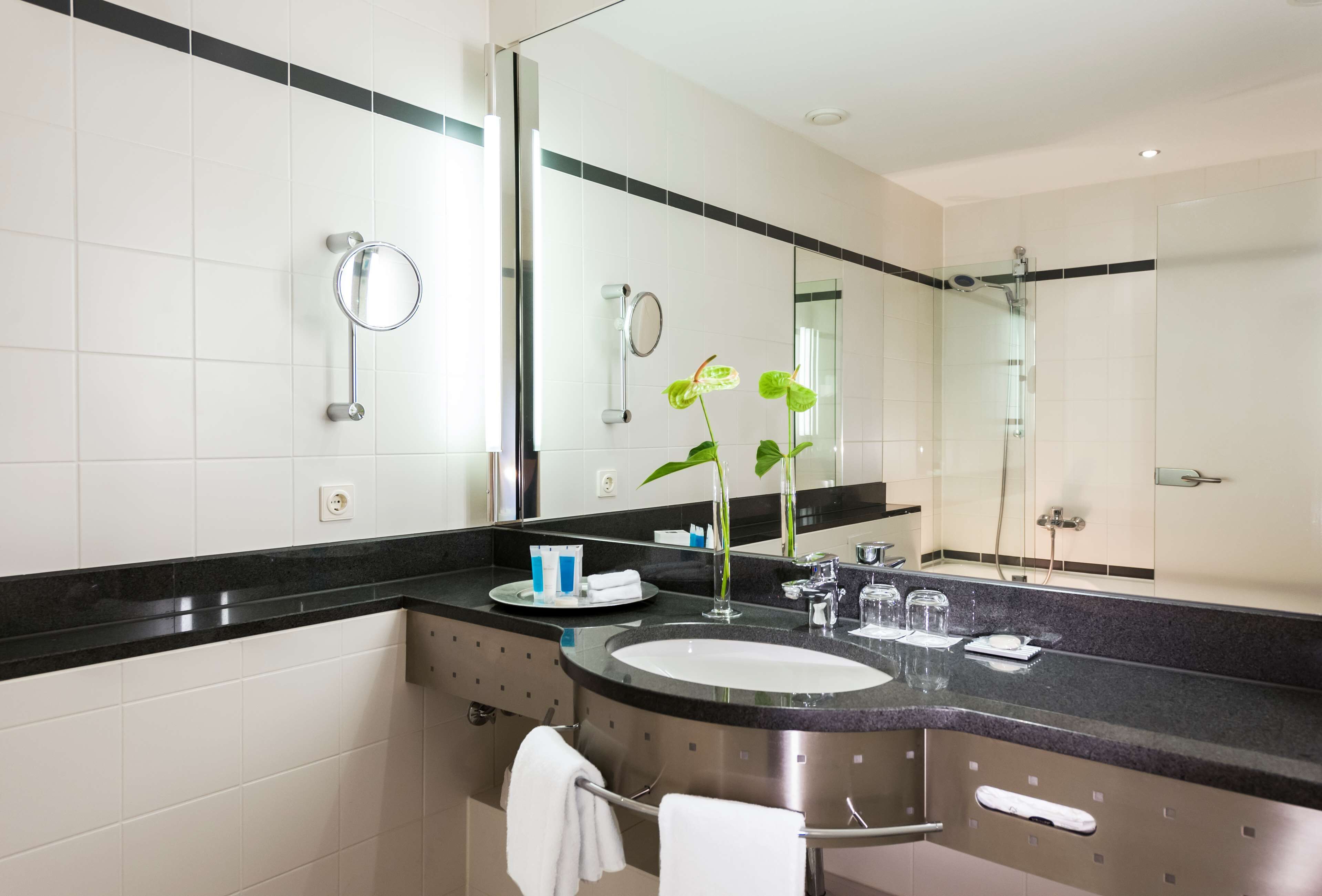 Une salle de bain moderne avec un grand miroir, un lavabo et une douche.