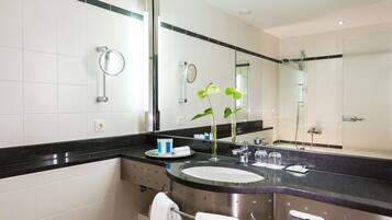 Une salle de bain moderne avec un grand miroir, un lavabo et une douche.