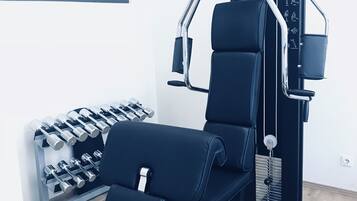 Een sportschool met een pull-up bar, een gewichtbank en dumbbells.