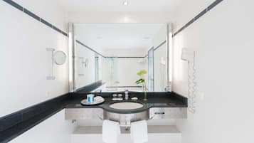 A modern bathroom with a large mirror, a round sink, and a towel rack.