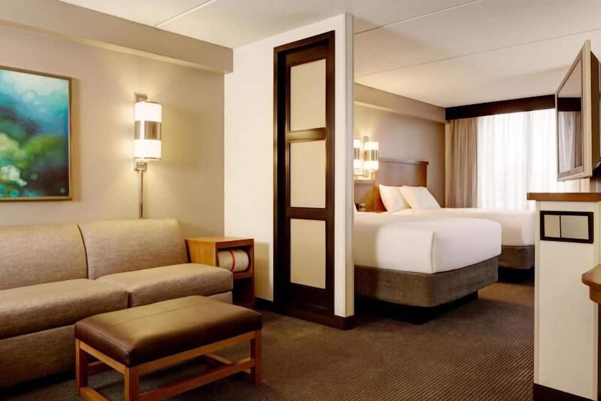 Una habitación de hotel con sofá, cama, escritorio y espejo.