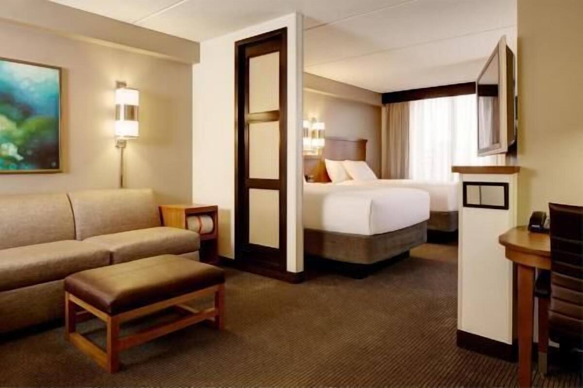 Una habitación de hotel con cama, sofá, una mesita y televisión.