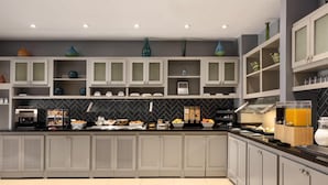 A modern kitchen with grey cabinets, a black backsplash, and various kitchen appliances.