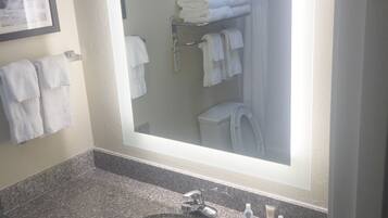 Un baño con encimera de granito, un lavabo, un espejo y un perchero con toallas dobladas.