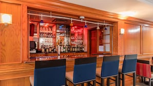 A bar area with wooden paneling, bar stools, and shelves stocked with bottles and glasses. - Comfort Inn & Suites Little Rock Airport (Little Rock)