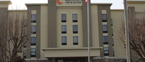 Un bâtiment de la chaîne Comfort Inn & Suites, avec une façade plate, de nombreuses fenêtres et un parking situé à l’avant.