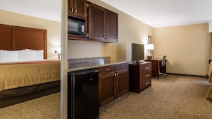 A hotel room with a bed, kitchenette, desk, and a television. - Comfort Inn & Suites Little Rock Airport (Little Rock)