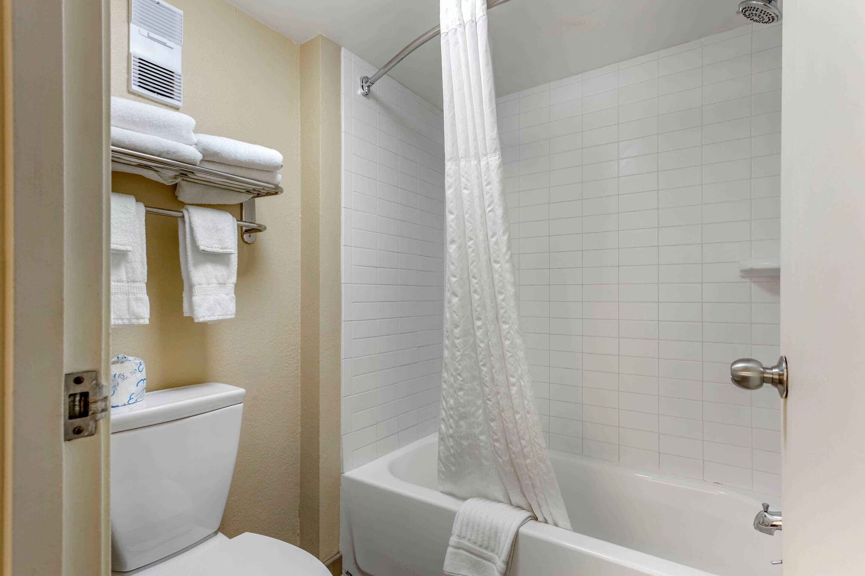 Une salle de bain équipée de toilettes, d’une baignoire et d’un rideau de douche.