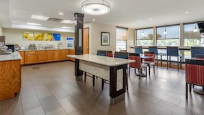 A modern dining area with a long counter, wooden cabinets, and a large window providing natural light. - Comfort Inn & Suites Little Rock Airport (Little Rock)