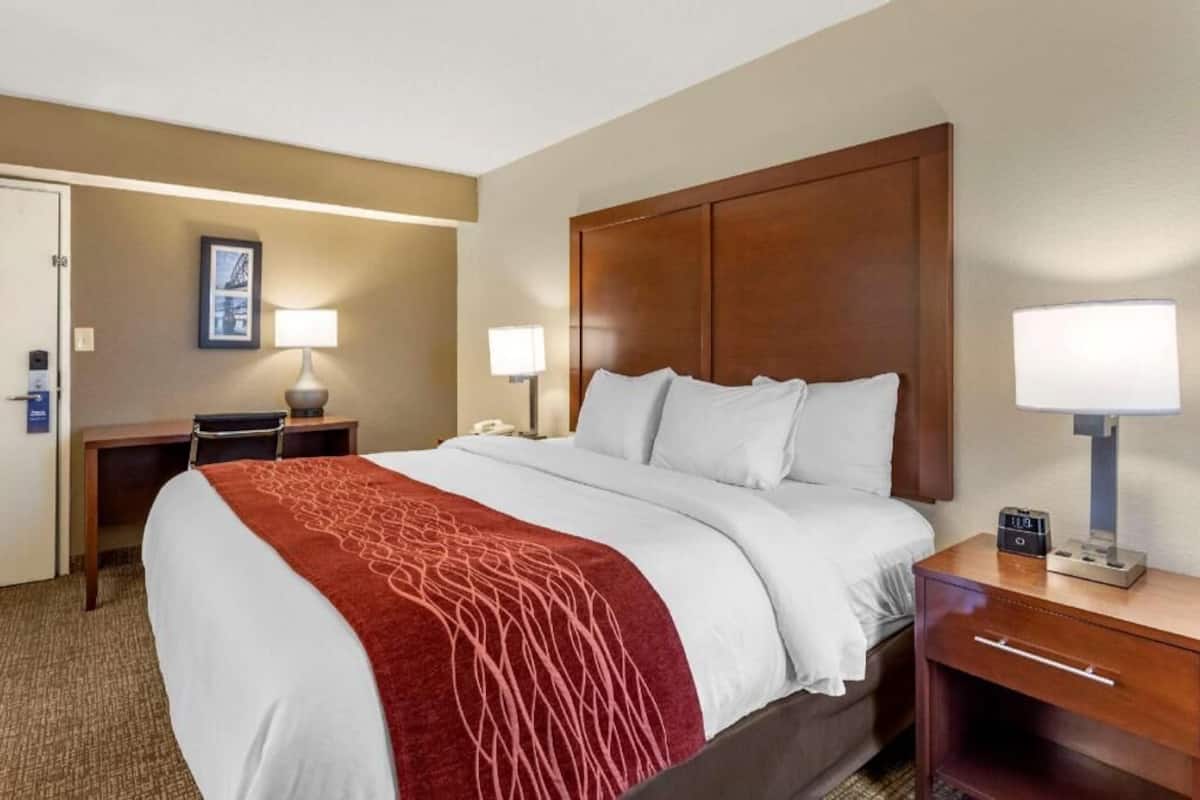 A hotel room with a large bed, bedside tables, a desk, and a chair.