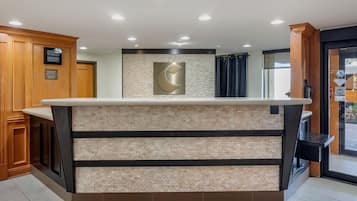 A reception area with a counter, wooden cabinets, a clock, and a wall-mounted logo.