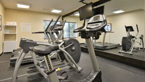 Une salle de sport équipée de tapis de course, d’un vélo d’appartement et d’une machine de musculation.