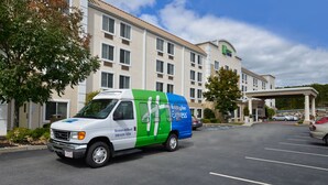 Un hôtel Holiday Inn Express doté d’un parking et d’un fourgon de livraison vert et blanc garé devant.