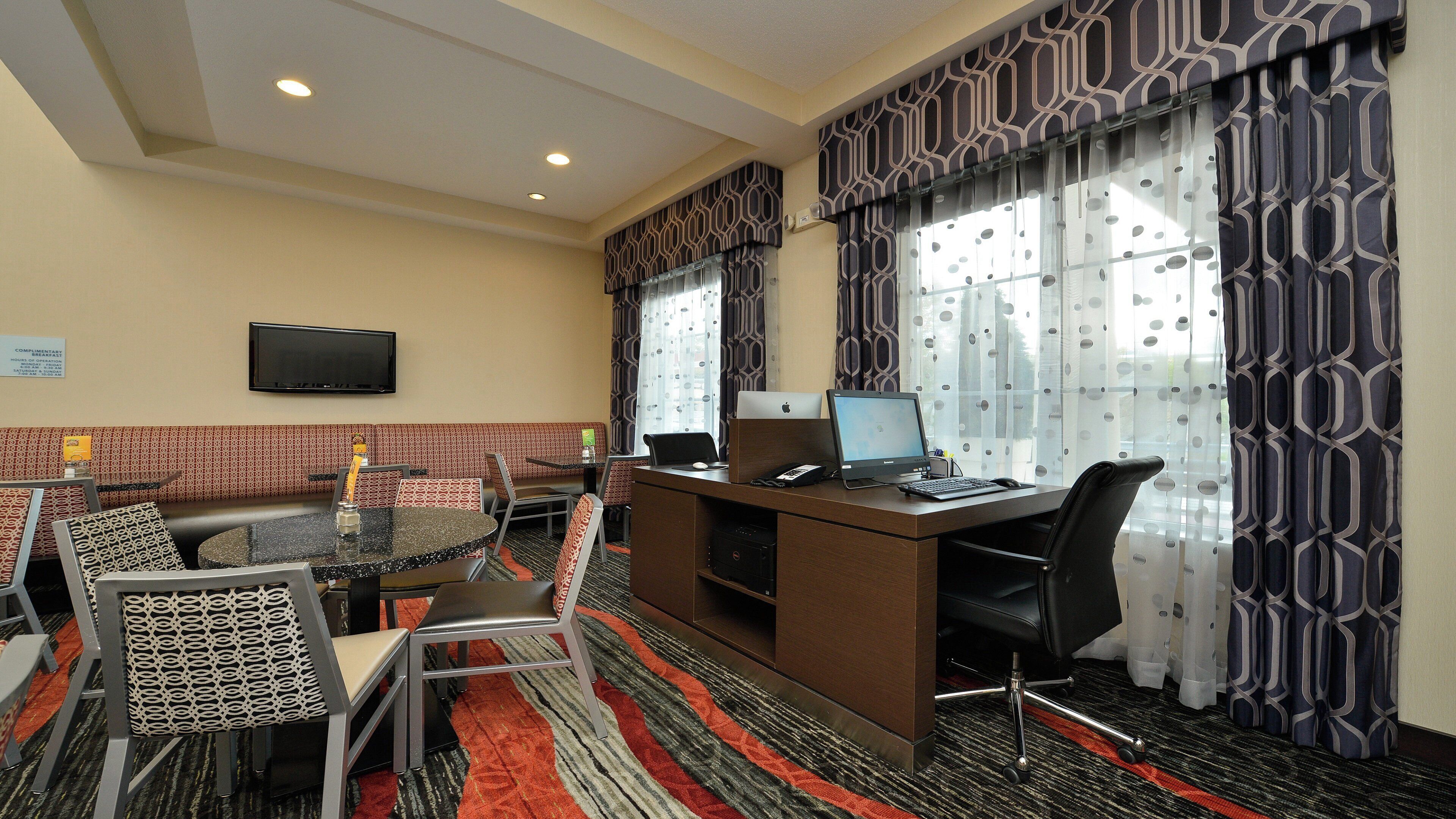 Habitación de hotel con escritorio, computadora y zona de estar.