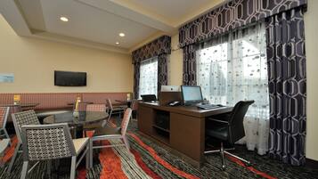 Habitación de hotel con escritorio, computadora y zona de estar.