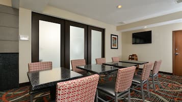 A conference room with a large table, multiple chairs, a television, and a door.