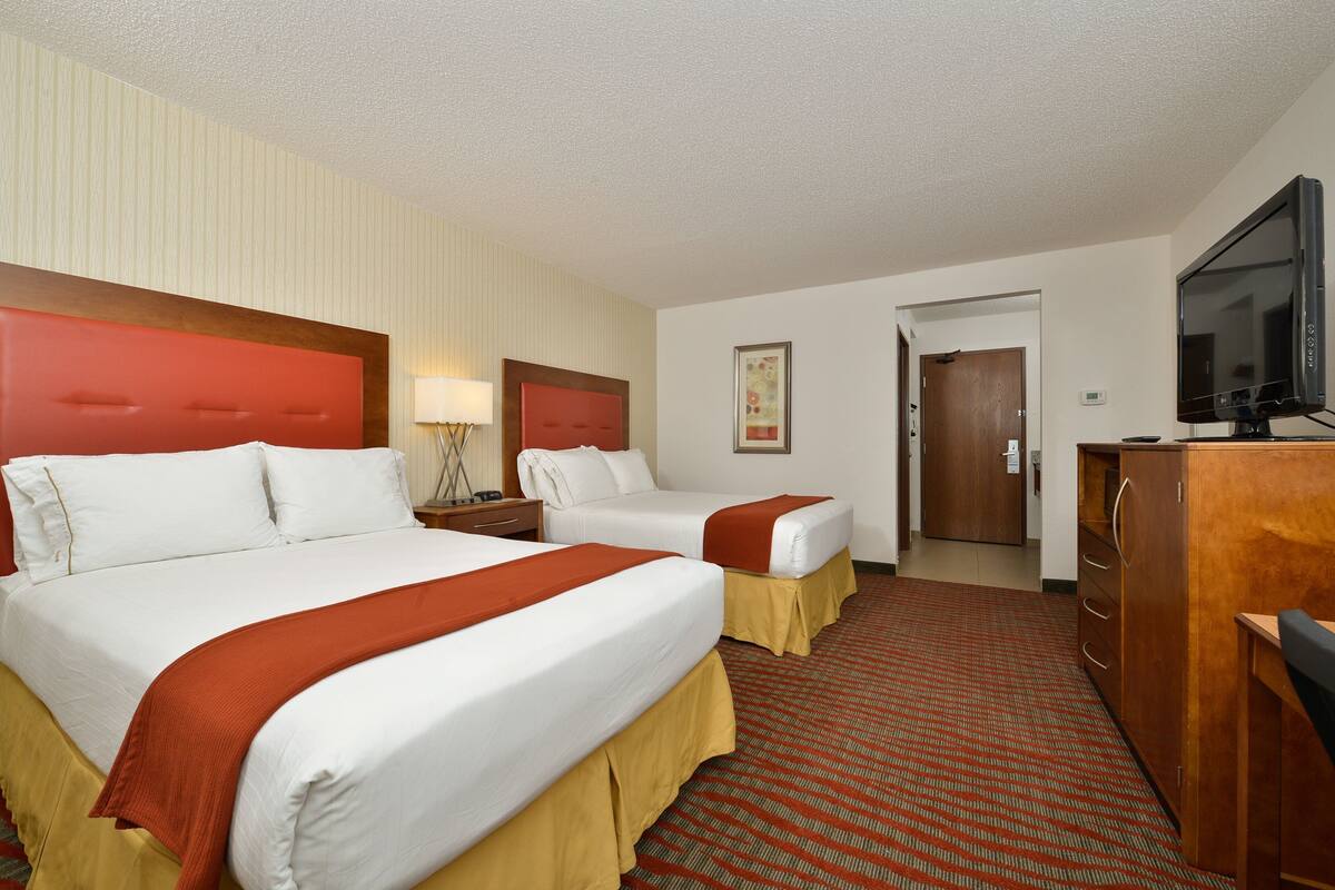 Une chambre d’hôtel avec deux lits, une télévision, un bureau et une commode.