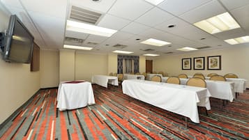 Une salle de conférence équipée de tables, de chaises, d’un téléviseur et d’un tapis à motifs.
