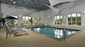 Une piscine intérieure avec des chaises longues et un parasol bleu.